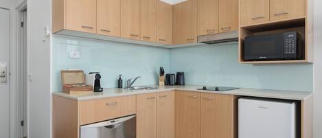 A compact kitchen with wooden cabinets, a dishwasher, a microwave, and a sink.
