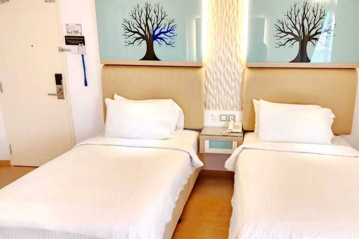 A double room with two beds, a nightstand with a phone, and a wall-mounted mirror.