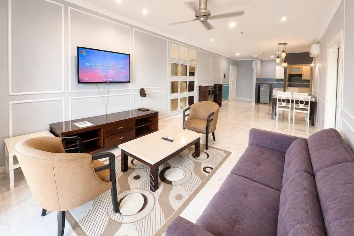 A modern living room with a sofa, chairs, a coffee table, and a TV.