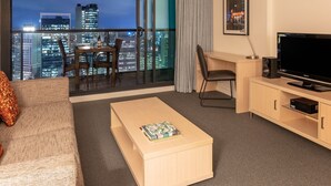Una habitación de hotel con balcón, televisión, escritorio y sofá.