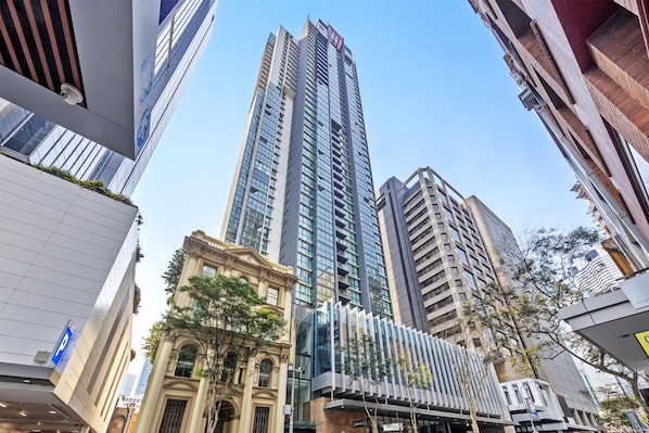 Un edificio moderno de rascacielos con fachada de vidrio, rodeado de otros edificios con diferentes estilos arquitectónicos.