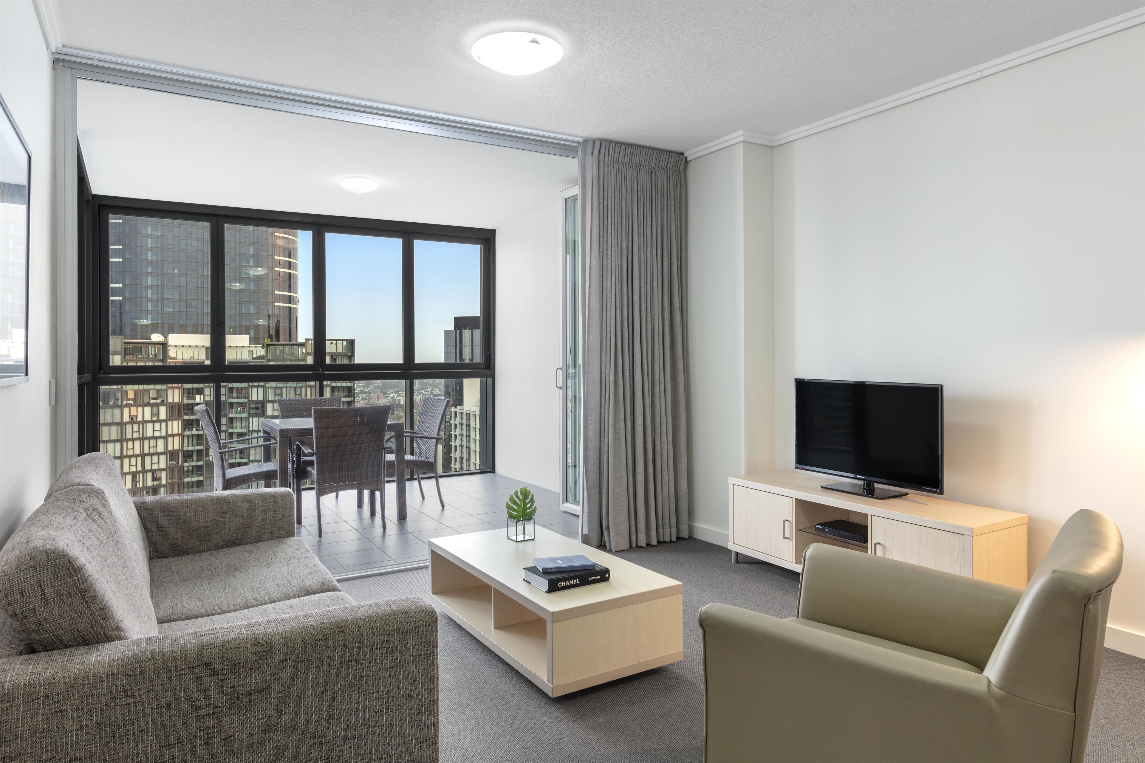 Uma sala de estar moderna com sofá, poltrona, mesa de centro e TV de tela plana.