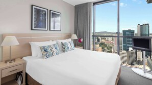 A hotel room with a large bed, two bedside tables, a TV, and a window with a city view. - Oaks Brisbane on Charlotte Suites (Brisbane)