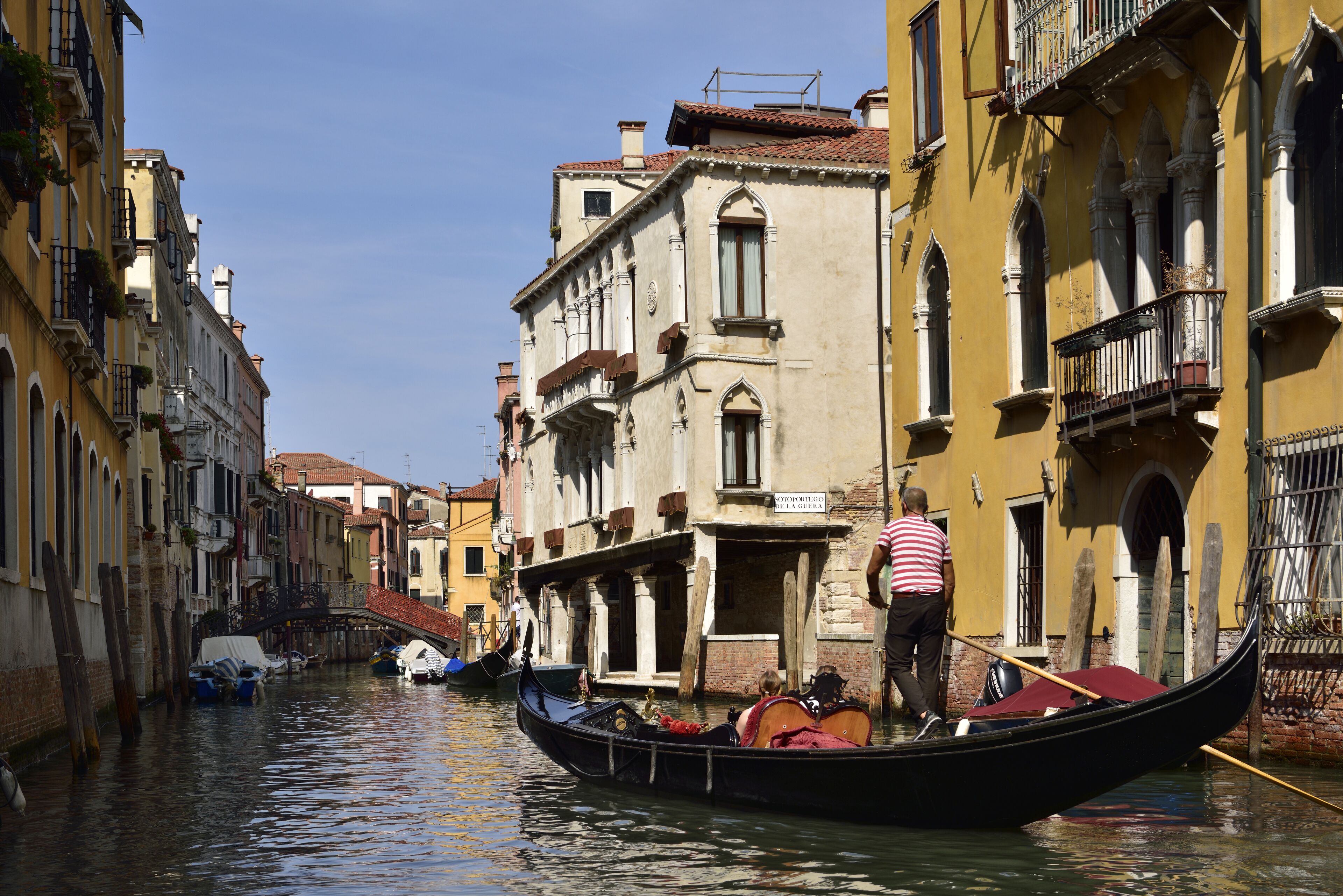 Un canal où l’on peut faire une promenade en gondole, des bâtiments dotés de balcons et un pont.