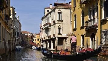 Un canal où l’on peut faire une promenade en gondole, des bâtiments dotés de balcons et un pont.