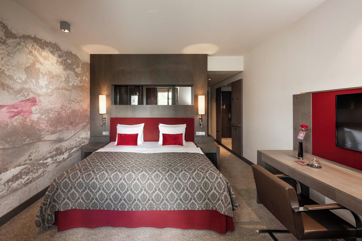 Ein modernes Hotelzimmer mit einem großen Bett, einem Schreibtisch und einem Fernseher.