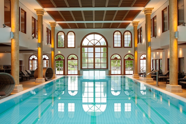 Una piscina techada, una piscina al aire libre, sombrillas
