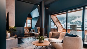 A modern living room with a large window, a fireplace, and a cozy seating area.