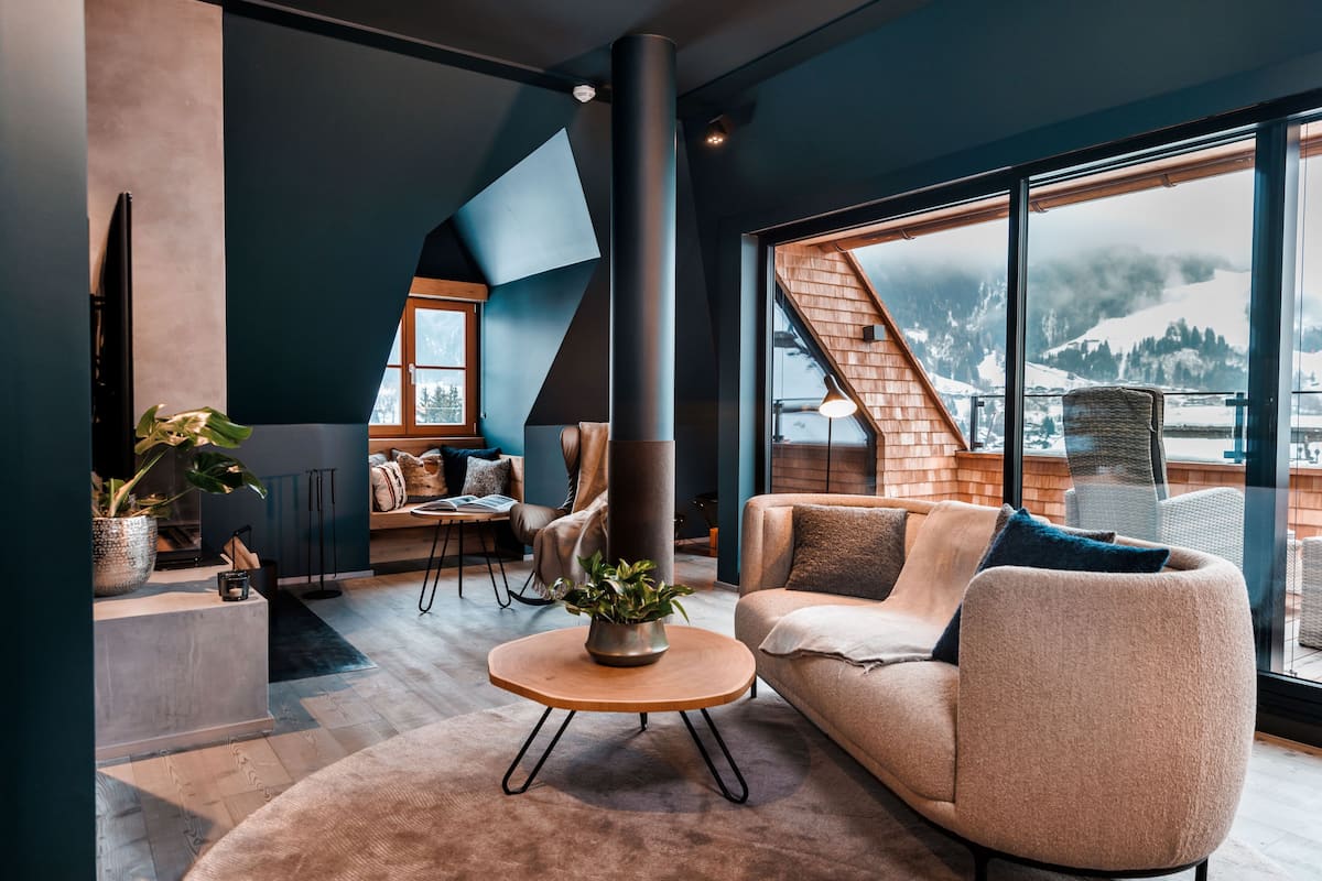 Ein modernes Wohnzimmer mit großem Fenster, Kamin und gemütlicher Sitzecke.