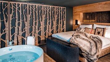 A modern bedroom with a large bed, a wooden headboard, a decorative wall panel, and a bathtub.