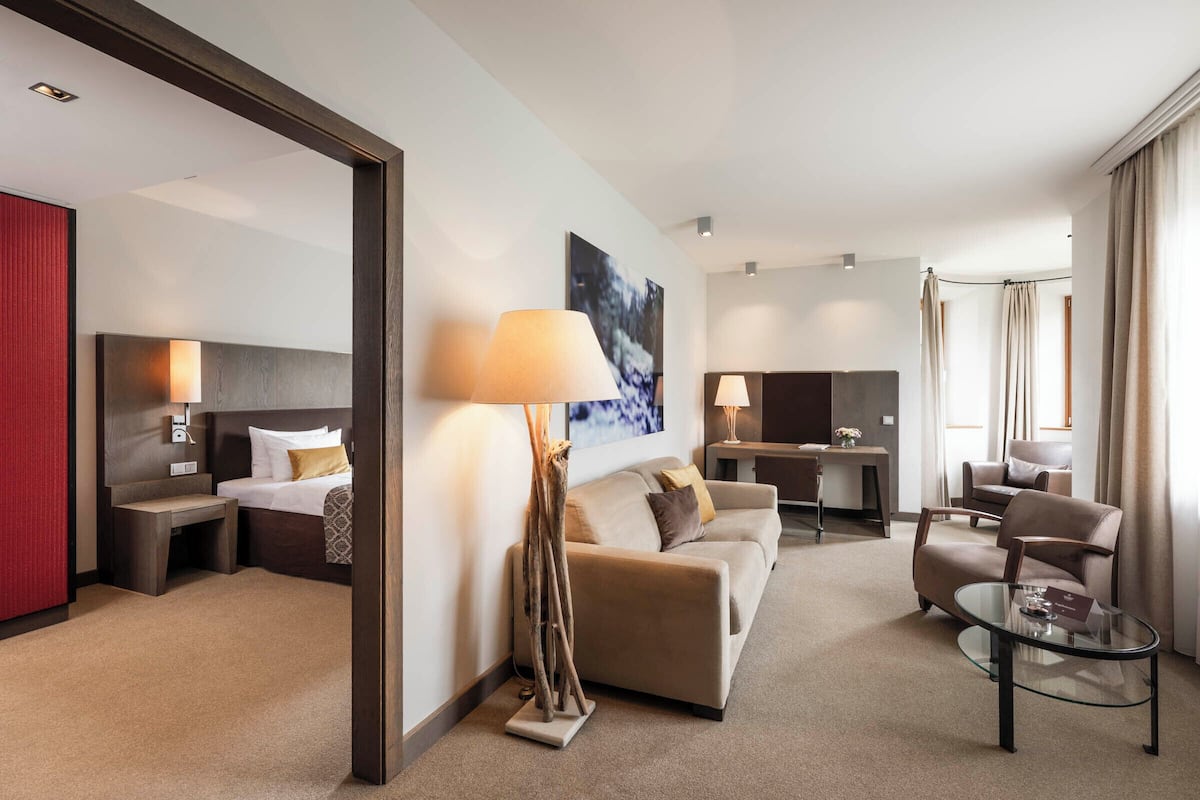 Ein modernes Hotelzimmer mit einem Bett, einer Couch, einem Schreibtisch und einem Glastisch.