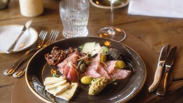A dining table with plates of food, cutlery, and glasses of wine.