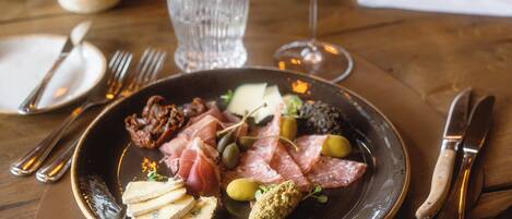 A dining table with plates of food, cutlery, and glasses of wine.