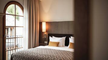 A hotel room with a large bed, a nightstand with a lamp, and a window with curtains.