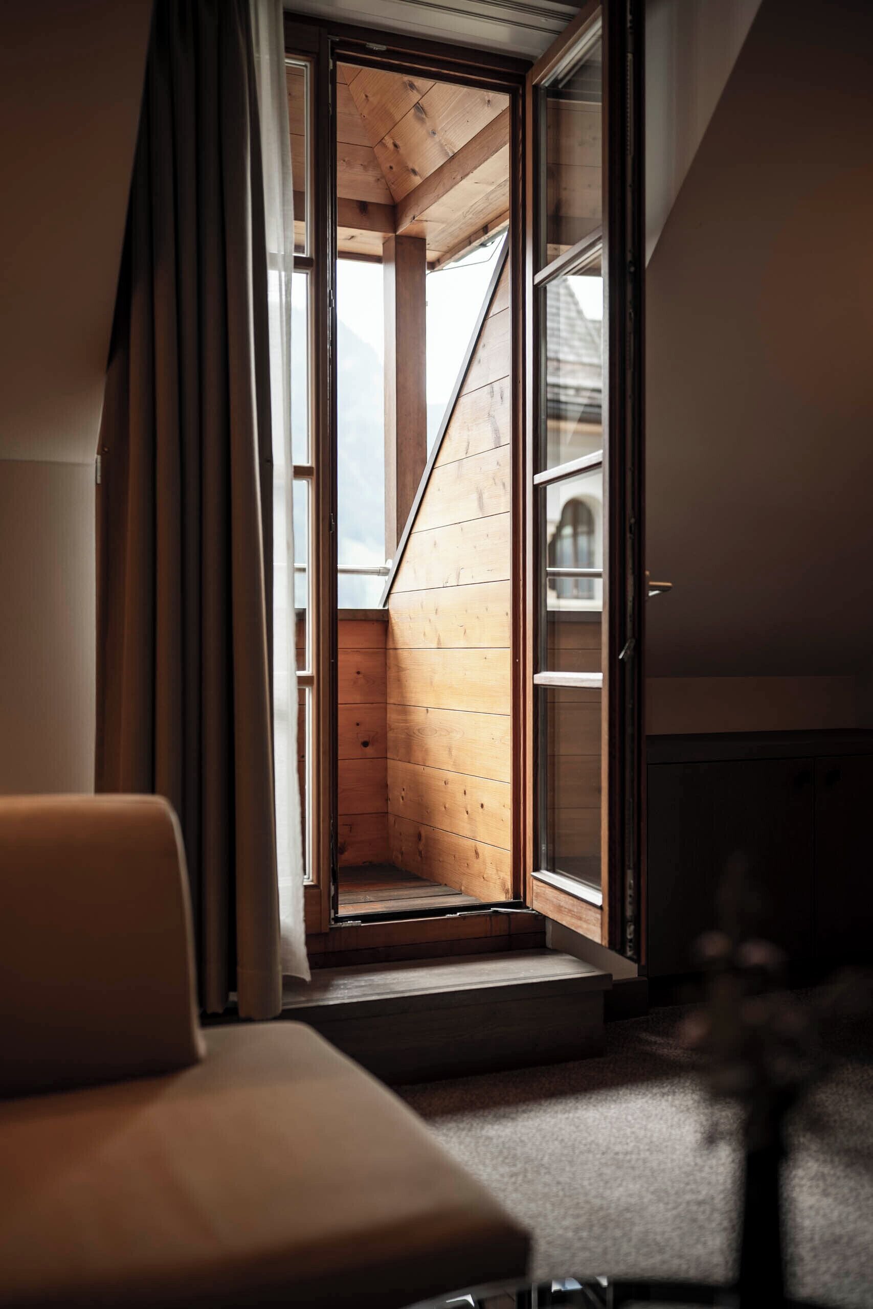 Een smalle trap die leidt naar een slaapkamer met een vide, muren van hout en een groot raam.