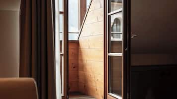 Una escalera estrecha conduce a un altillo con paredes de madera y un ventanal grande.