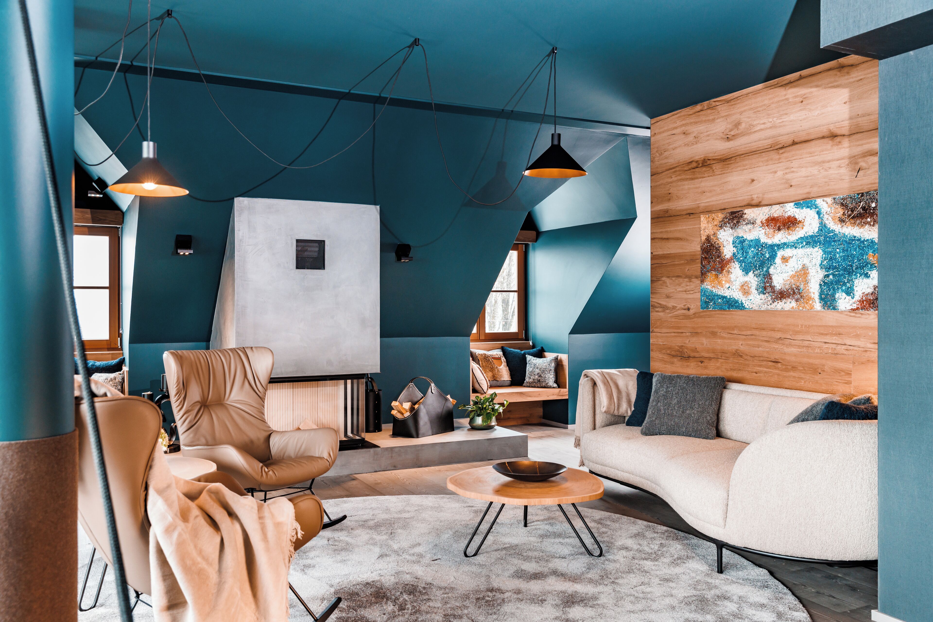 Una sala de estar moderna con un sofá, sillones, una mesa de centro e iluminación colgante.