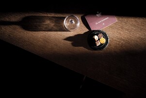 Una mesa de madera con un vaso, una caja de bombones y una pequeña vela.