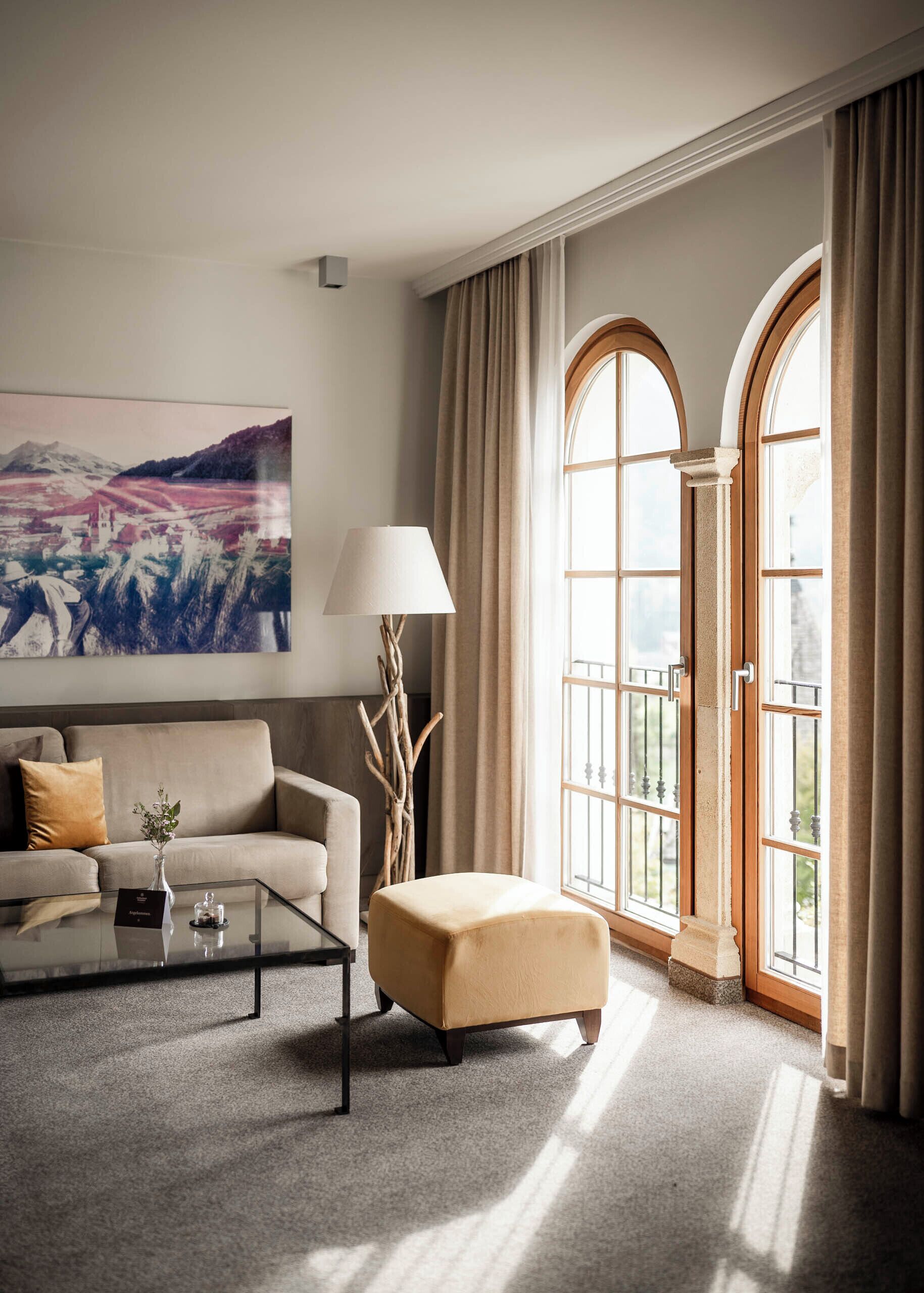 A modern living room with a sofa, ottoman, coffee table, and a painting on the wall.