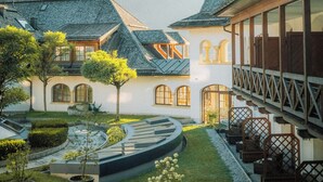 A courtyard with a circular garden, traditional buildings with sloped roofs, and a mountain in the background.