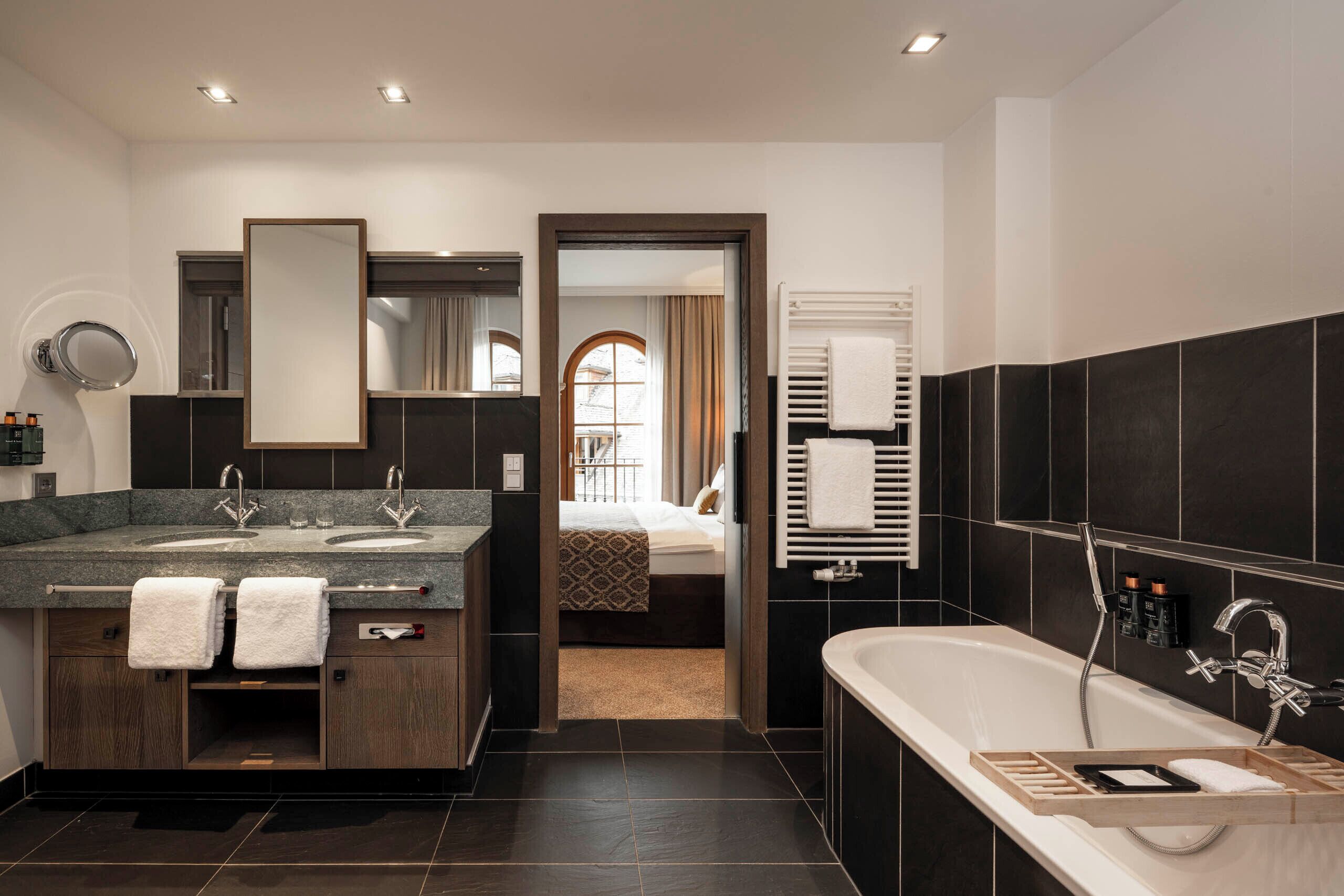 A modern bathroom with a dual sink vanity, a large mirror, a bathtub, and a walk-in shower.