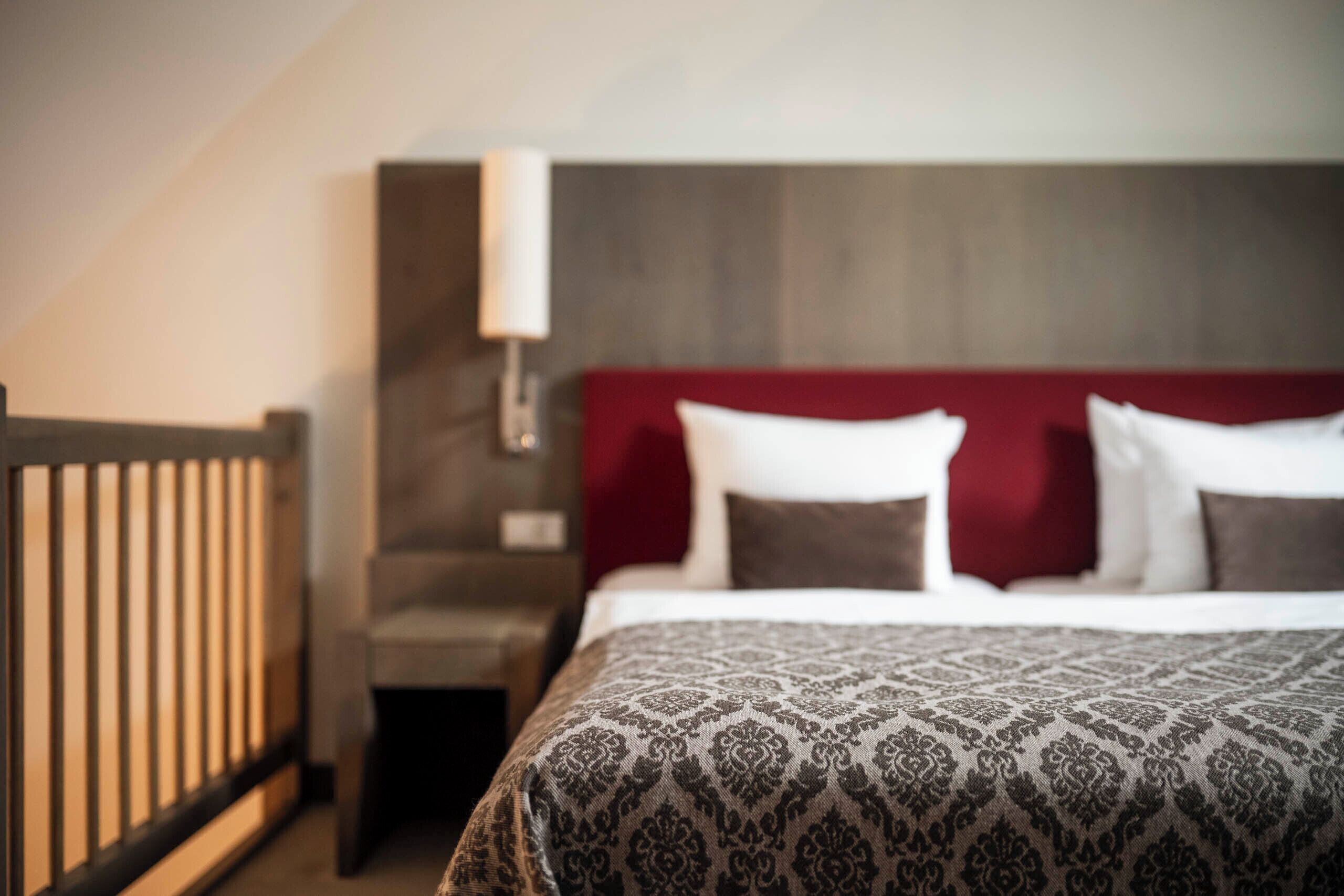 Et hotelværelse med en seng, et rødt sengegavl og et natbord.