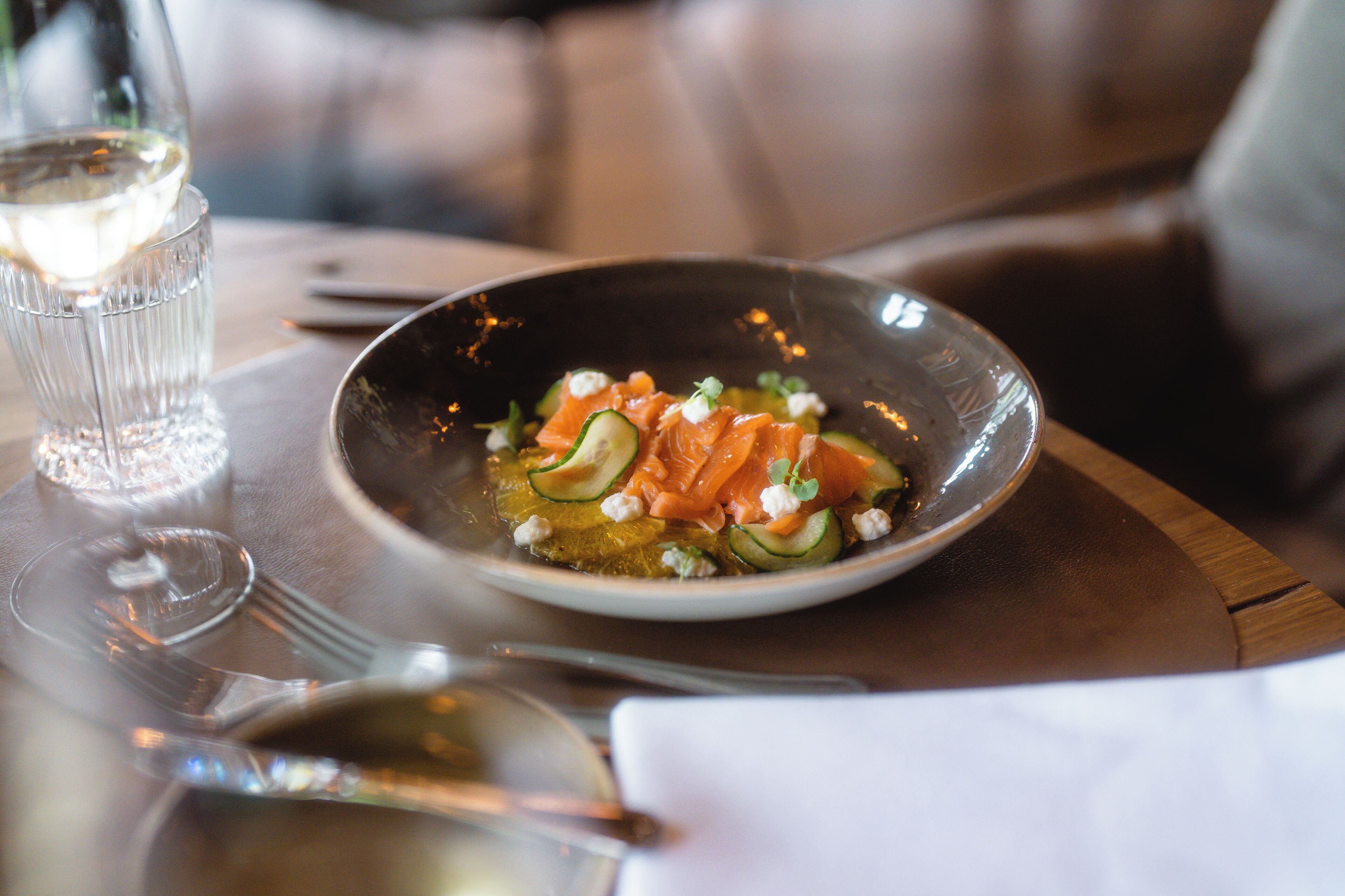 A plate of food with salmon and vegetables on a wooden table.