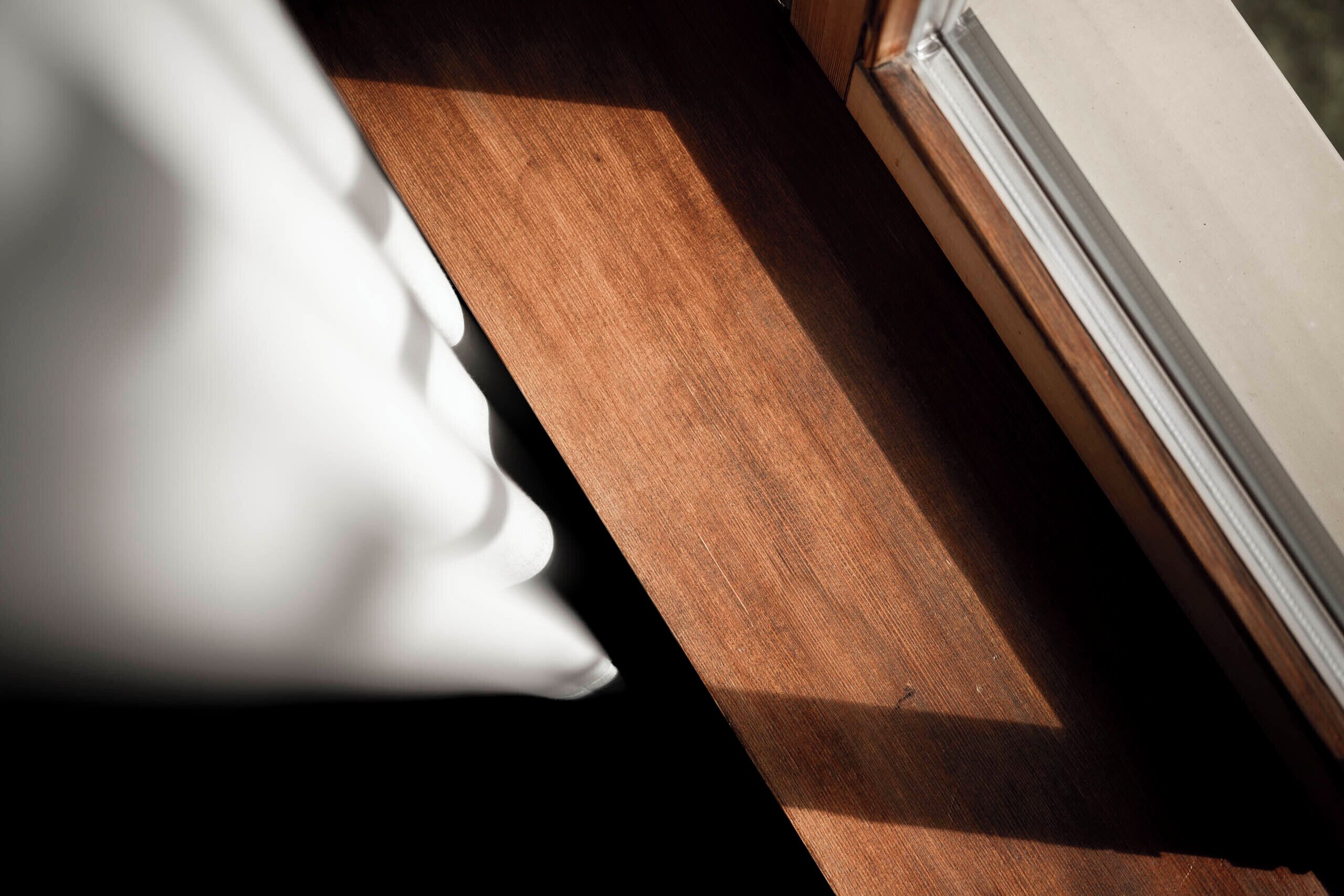 A wooden ledge and a white object, possibly a pillow, near a window.