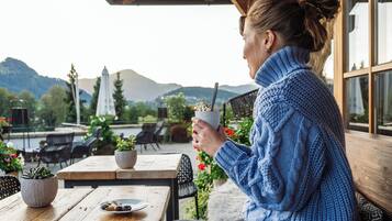 Une personne assise à une table en plein air, avec vue sur des montagnes et un lac.