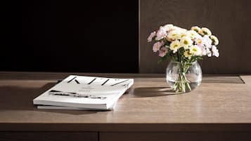 A wooden desk with a magazine and a vase of flowers.