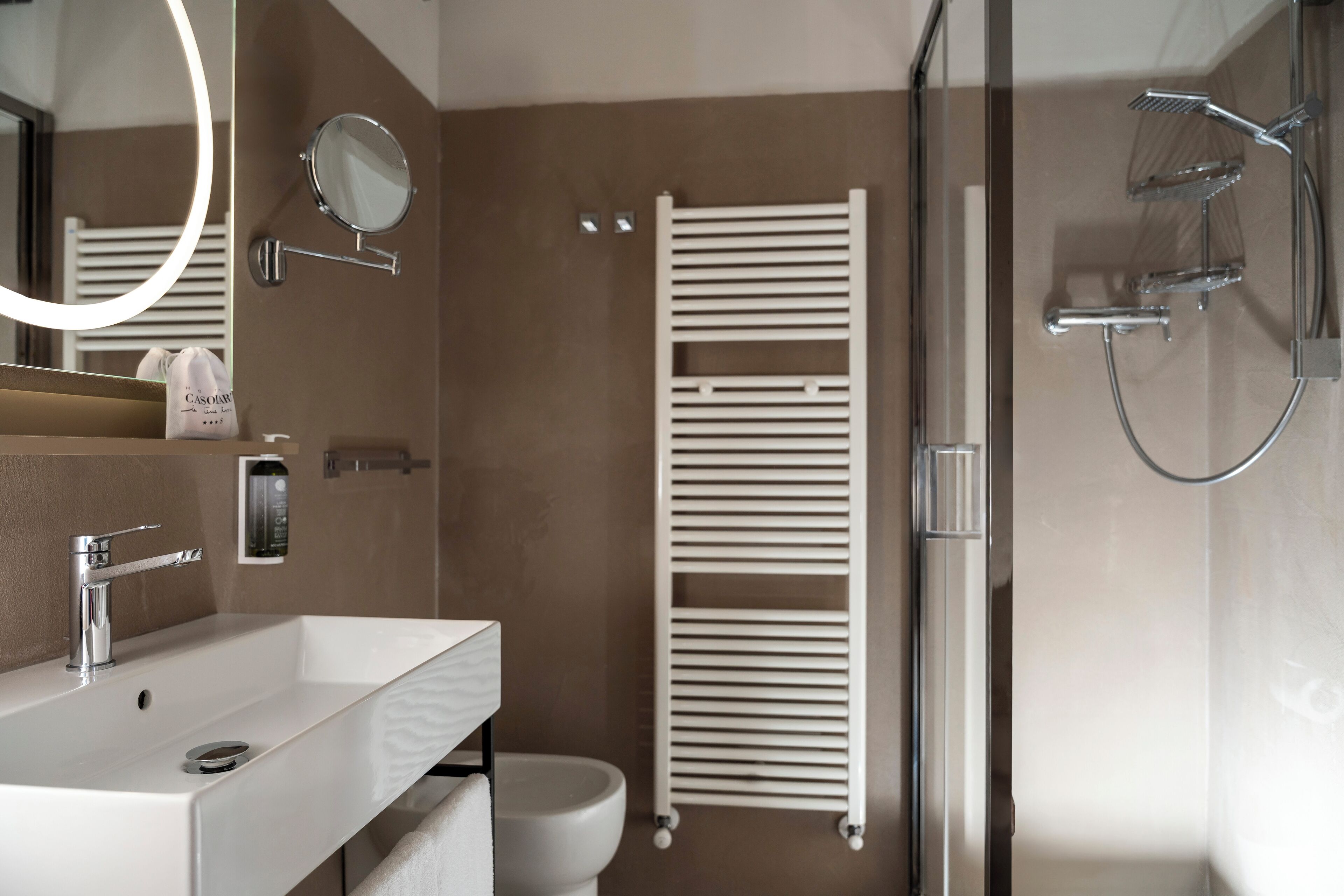A modern bathroom with a white sink, a mirror, a handheld showerhead, and a towel rack.