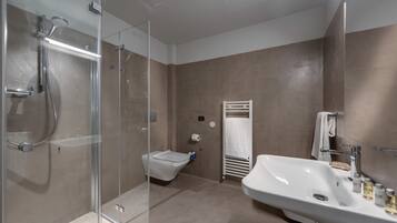 A modern bathroom with a glass-enclosed shower, a toilet, and a large sink with toiletries.