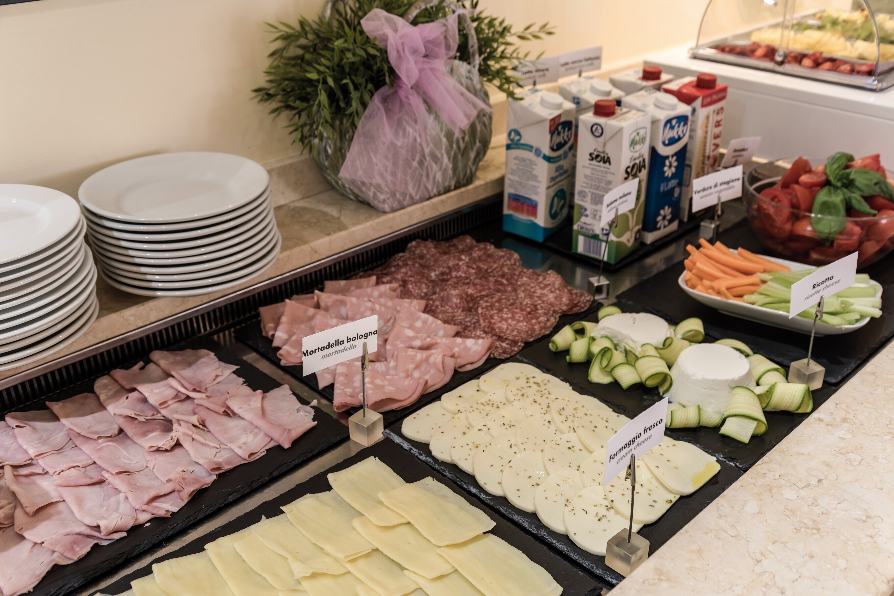 Un bufé con una variedad de alimentos, incluyendo carnes, quesos y verduras.