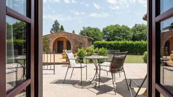 An outdoor patio with a stone building, two round tables, and four chairs.