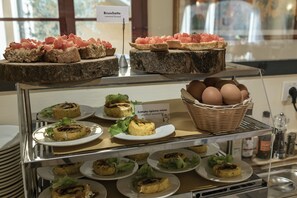 A buffet with various food items including Bruschetta, Frittata ripiena mista, and a basket of eggs. - Hotel Casolare Le Terre Rosse (San Gimignano)