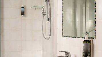 A modern bathroom with a white sink, a glass shower enclosure, and a large mirror with a colorful border.