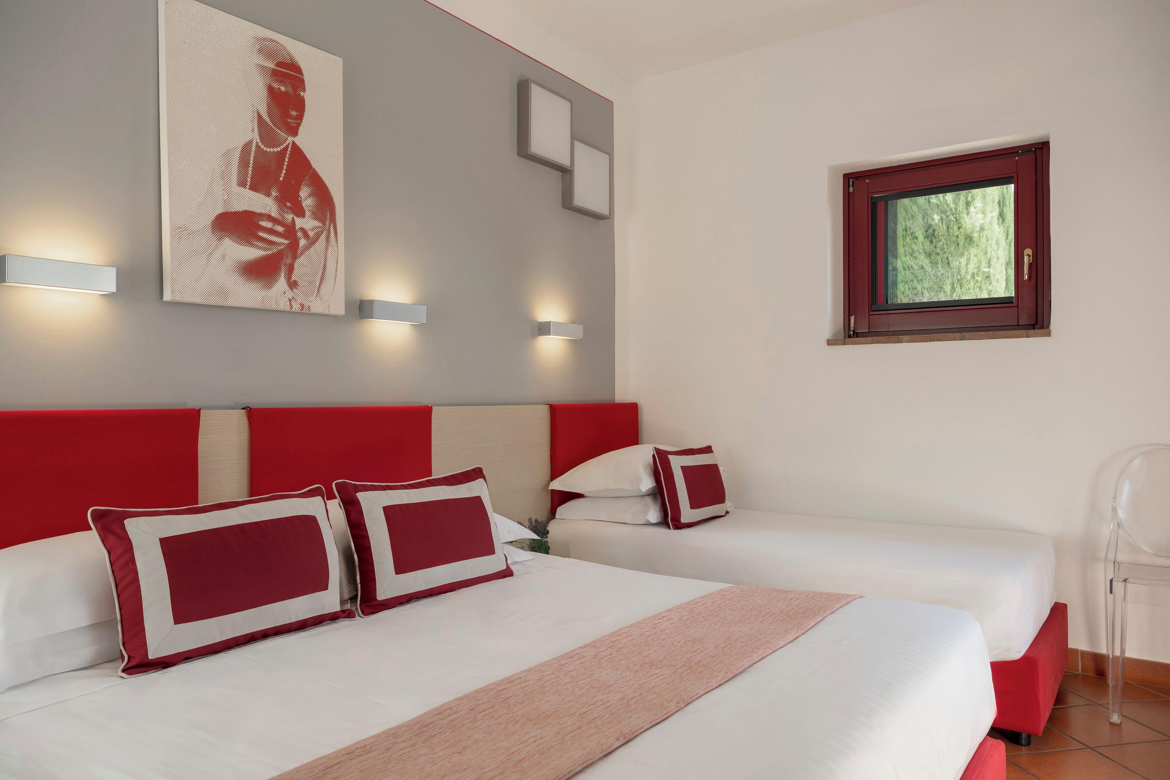 Habitación de hotel con cama, dos mesitas de noche, una ventana y una obra de arte colgada en la pared.