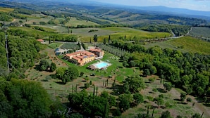 A large estate with a swimming pool, surrounded by lush greenery and rolling hills.
