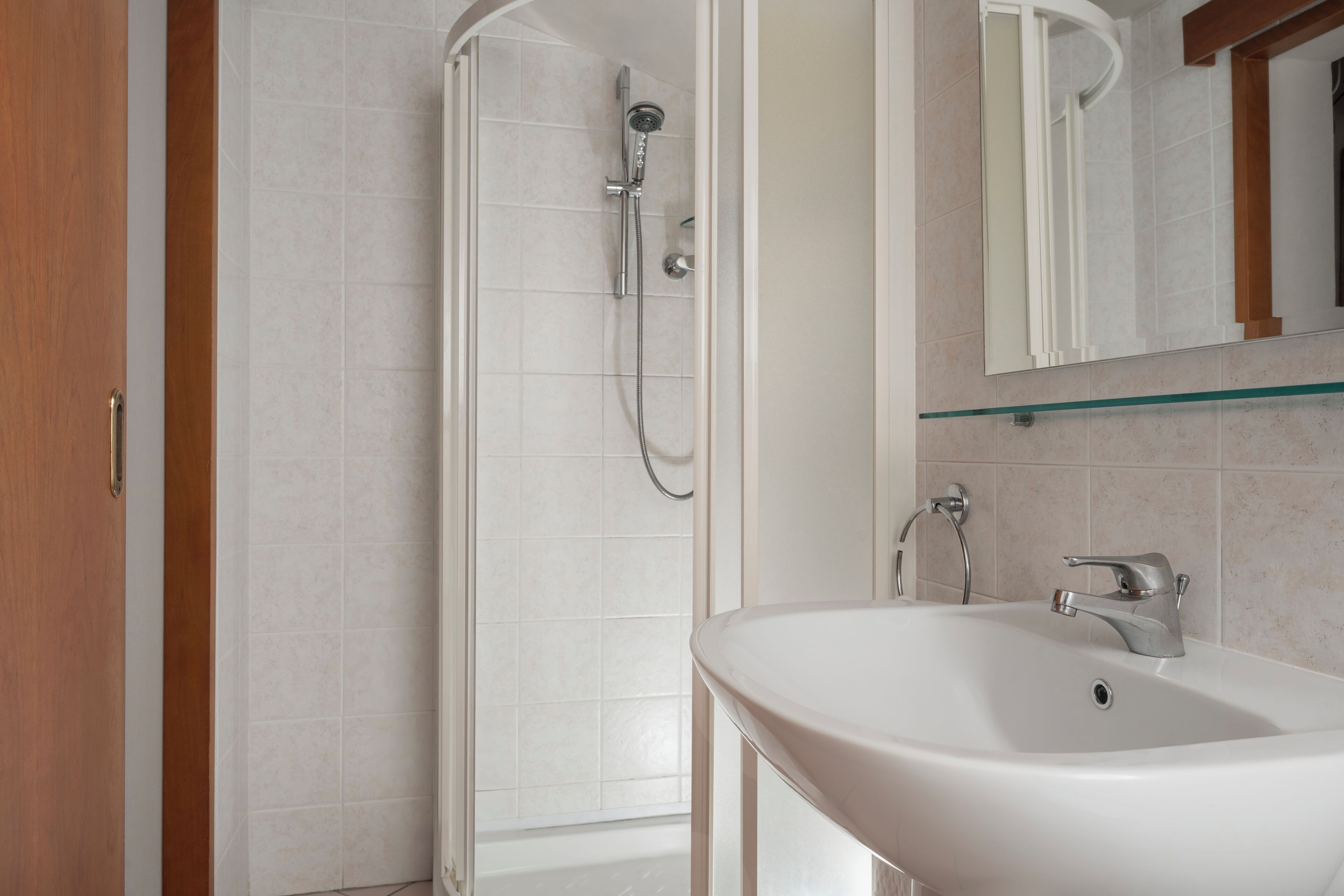 A bathroom with a shower, a sink, and a mirror.
