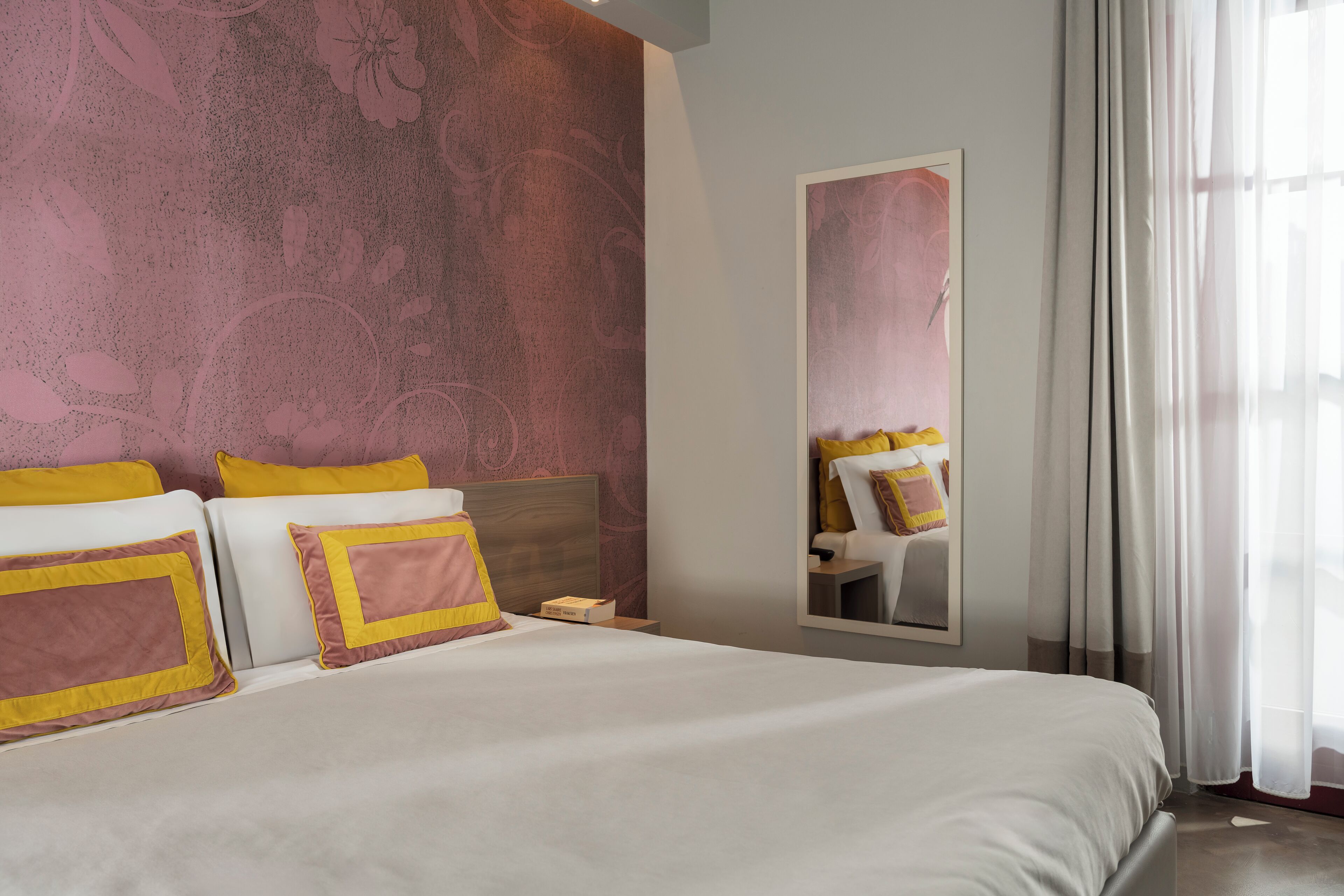 Una camera d'albergo con un letto grande, due comodini e uno specchio.