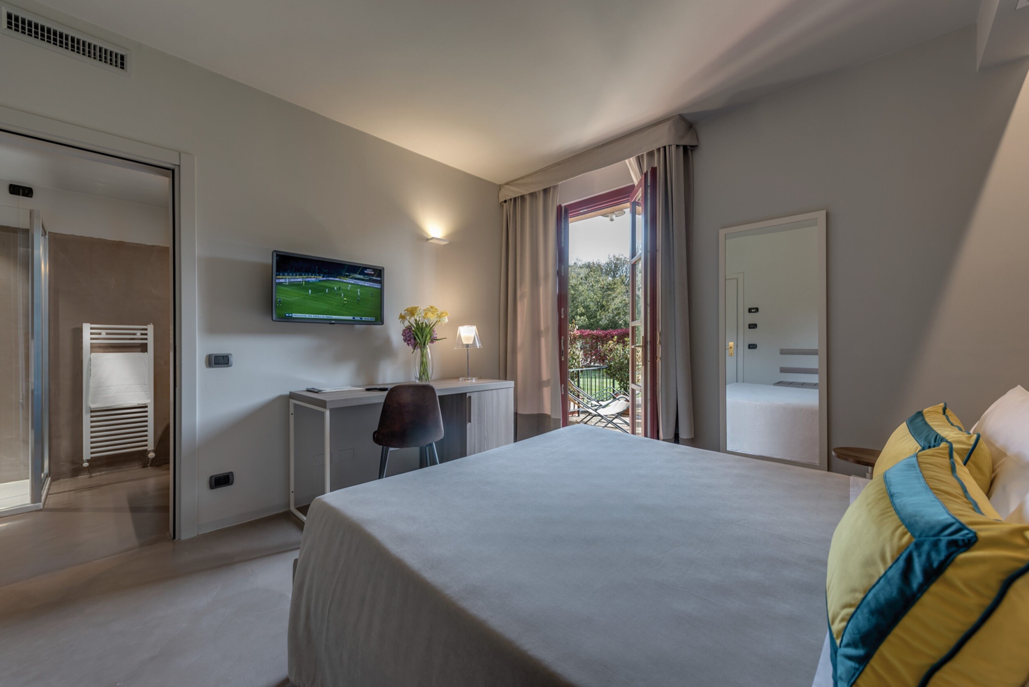 A hotel room with a bed, a desk, a TV, and a window with curtains.