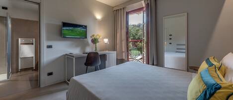 A hotel room with a bed, a desk, a TV, and a window with curtains.