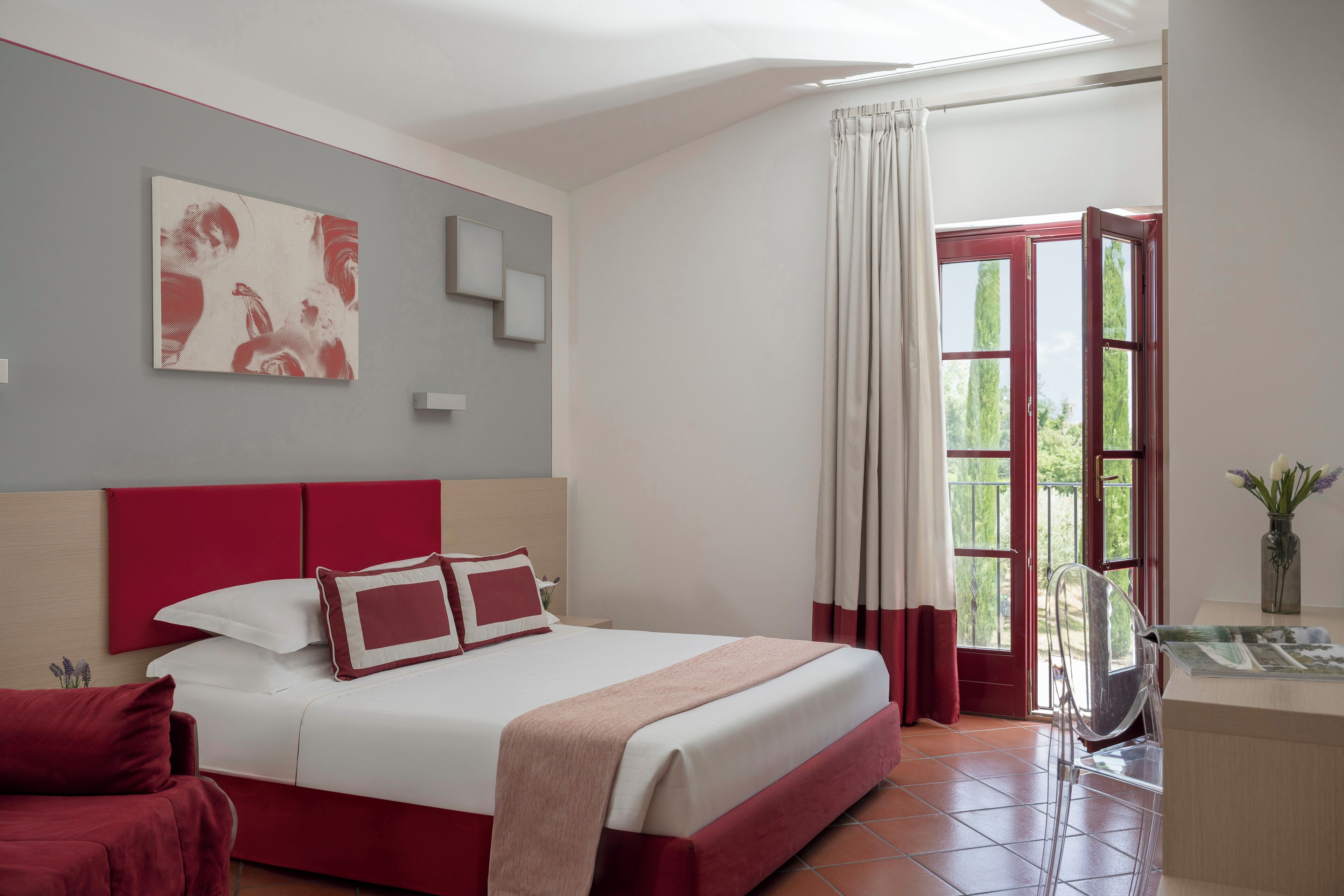 A hotel room with a bed, a desk, a chair, and a window with curtains.