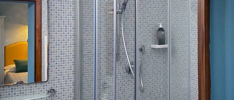 A modern bathroom with a glass-enclosed shower, a sink, and a mirror.