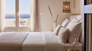 A bedroom with a bed, bedside table, and a view of the sea.