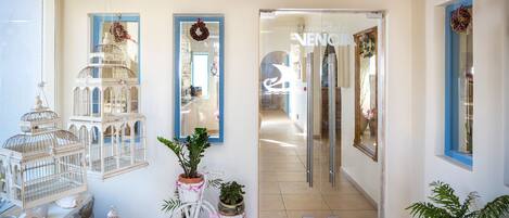 A hotel entrance with a glass door, a white bicycle, and decorative birdcages.