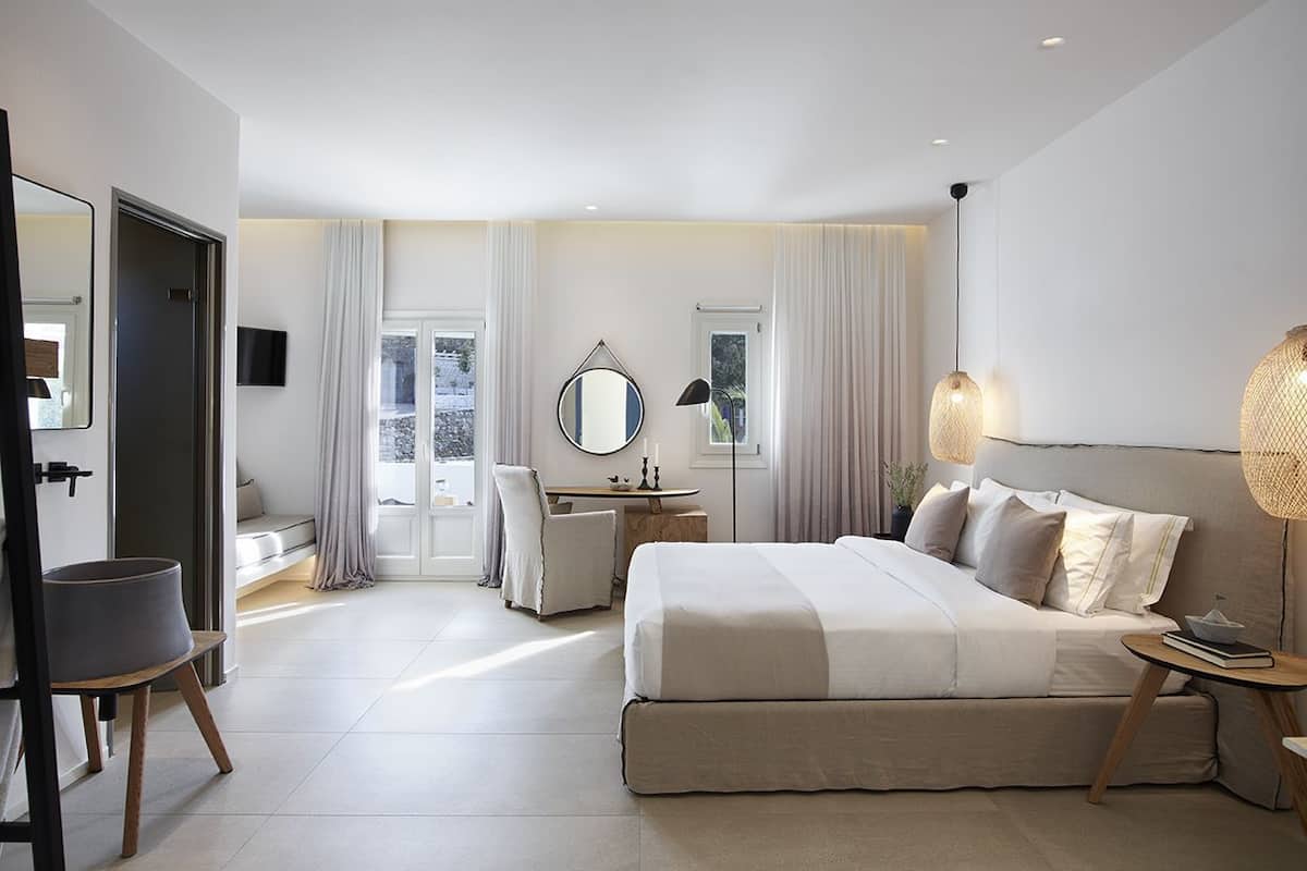 Een moderne hotelkamer met een groot bed, een bureau, een stoel en een spiegel.