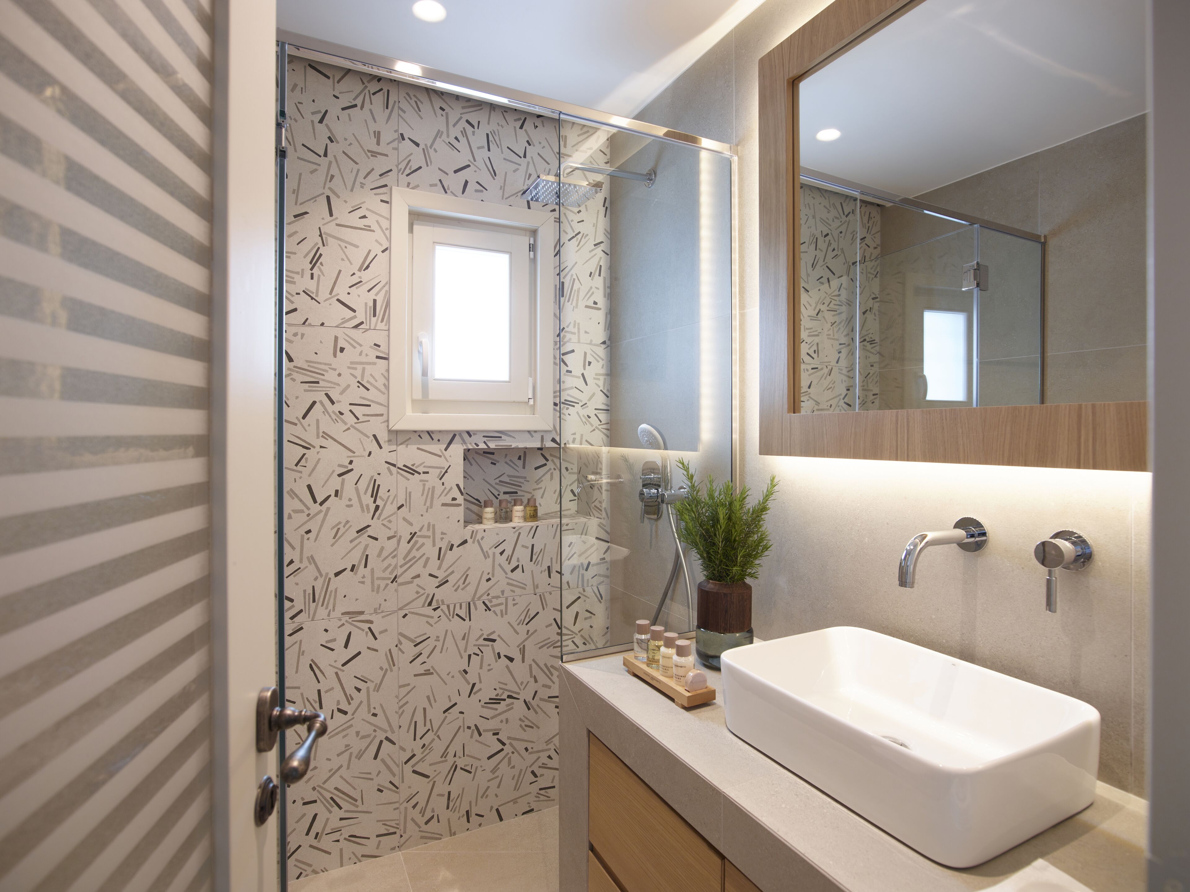 A modern bathroom with a glass-enclosed shower, a large mirror, and a white sink.