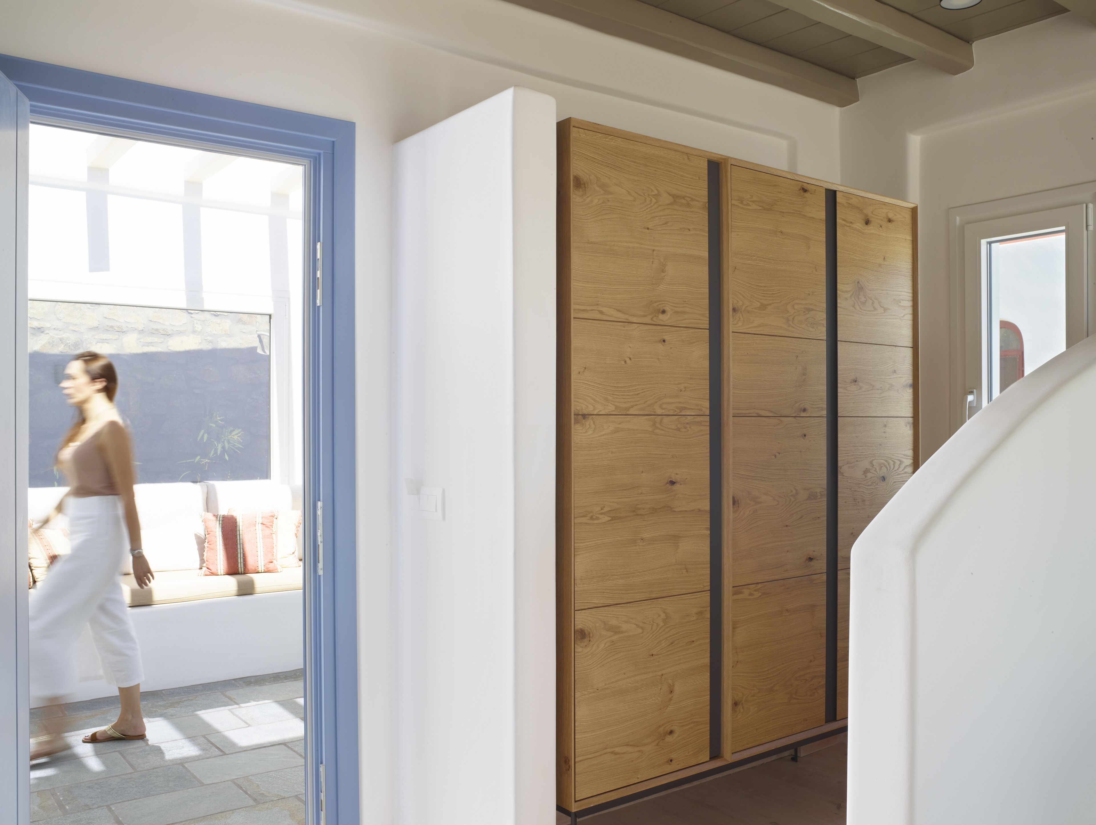 Une pièce avec une grande armoire en bois, un mur blanc et une porte donnant sur un balcon.