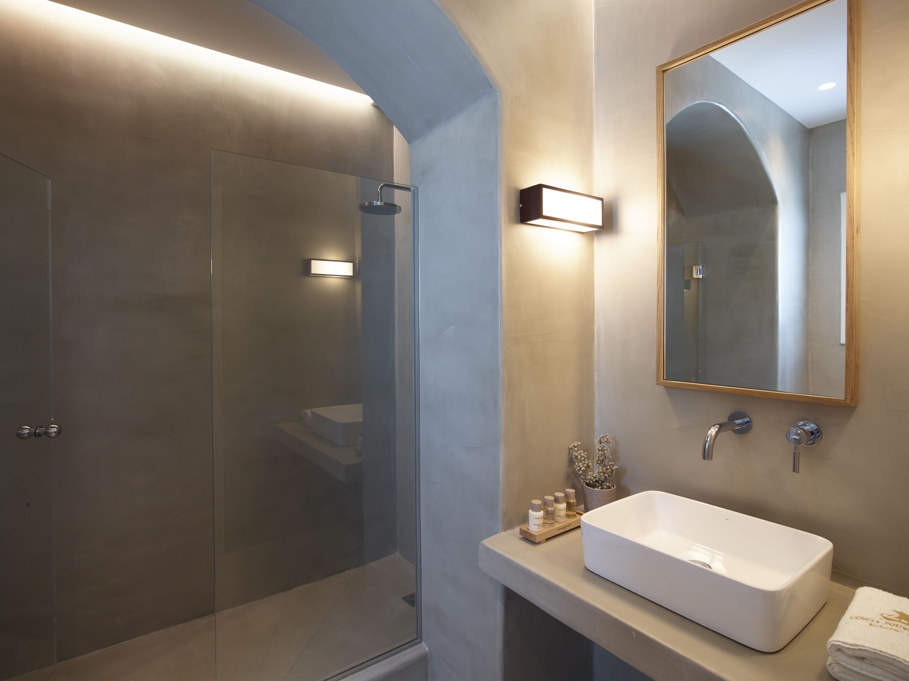 A modern bathroom with a glass-enclosed shower, a white sink, and a large mirror.
